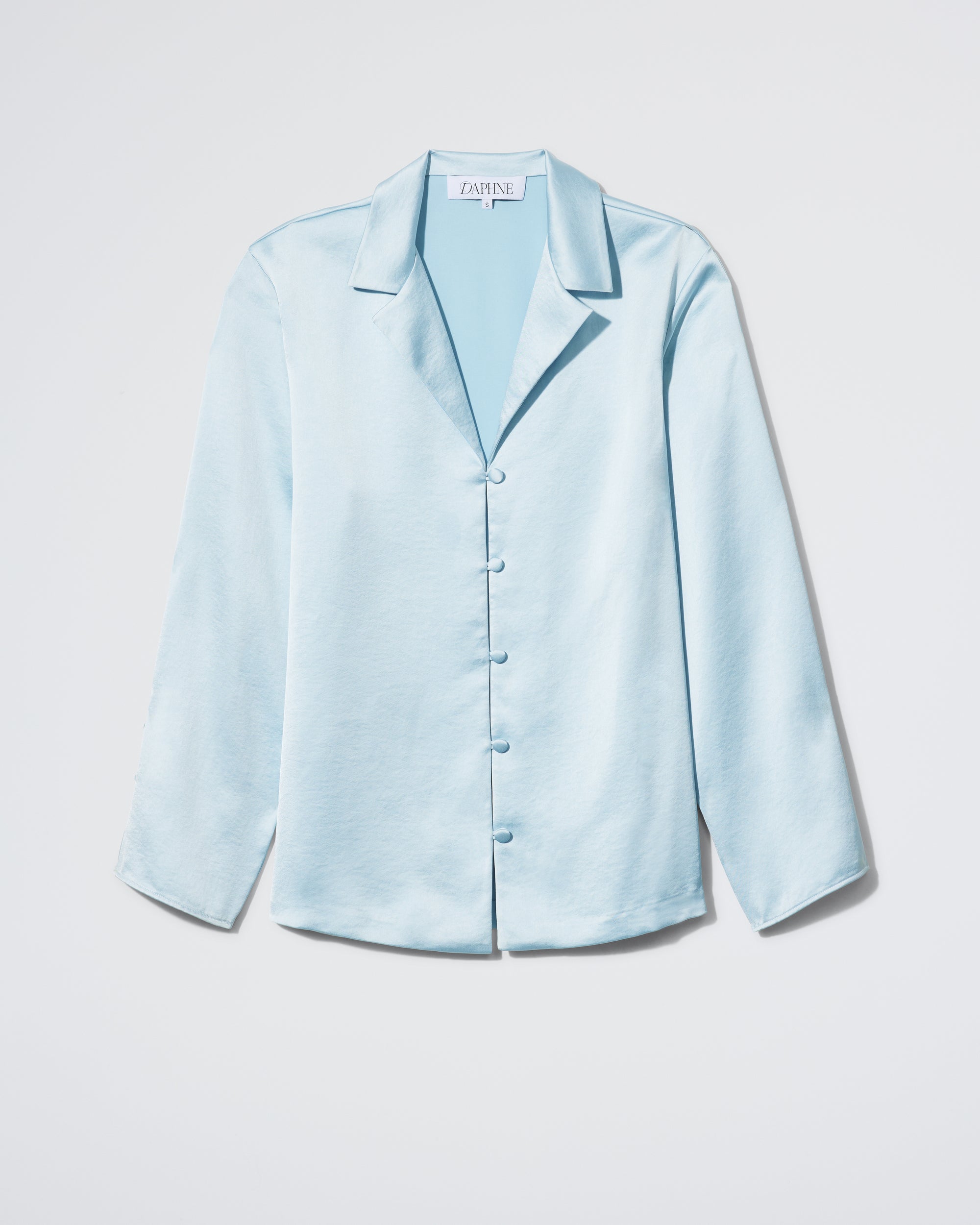 The Plus One Shirt - Frost by Daphne is a light blue, long-sleeved satin button-up with a notched collar, displayed against a plain white background.