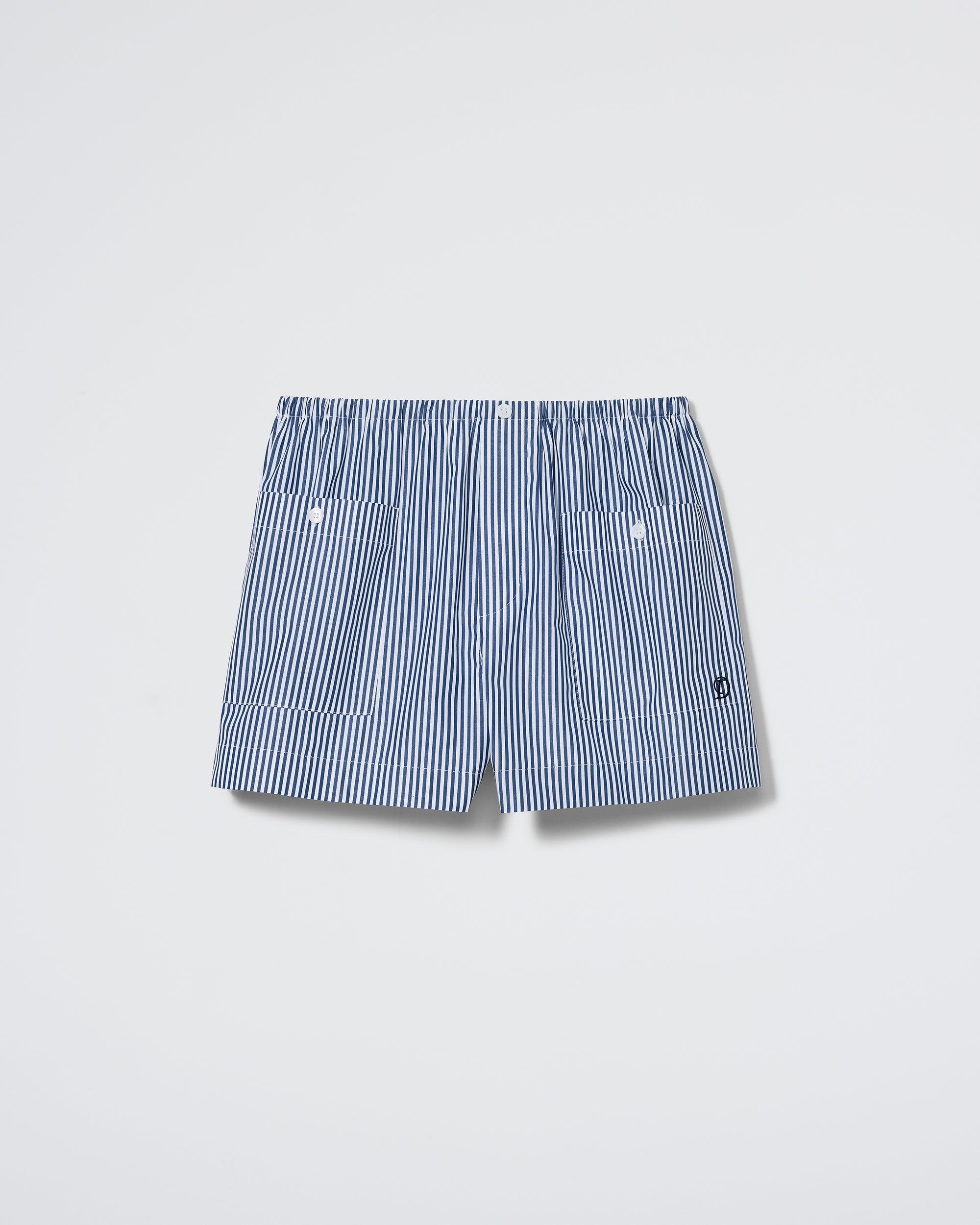 The Shut Eye Boxer - Midnight Stripe by Daphne features blue and white vertical stripes, an elastic waistband, and two front buttons, shown on a plain white background.